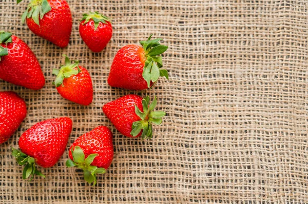 Acostado plano con fresas naturales sobre tela de saco con espacio de copia - foto de stock