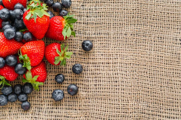 Top view of strawberries and fresh blueberries on sackcloth — Stock Photo