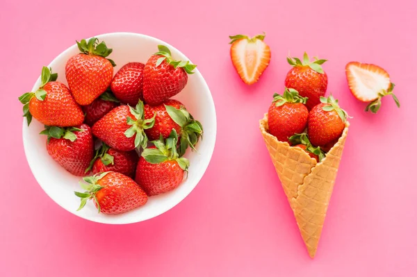 Draufsicht auf natürliche Erdbeeren in Schale und Waffelkegel auf rosa Oberfläche — Stockfoto