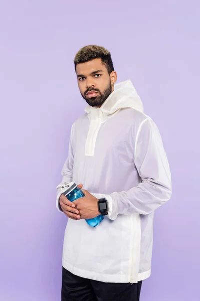 Homem americano africano na moda sportswear segurando garrafa de esportes isolados em roxo — Fotografia de Stock