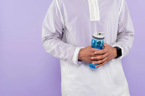Cropped view of african american man in trendy sportswear holding sports bottle isolated on purple — Stock Photo