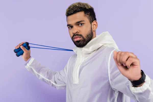 Bearded african american man holding skipping rope isolated on purple — Stock Photo