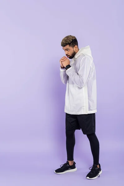 Toute la longueur de barbu homme afro-américain en vêtements de sport échauffement sur violet — Photo de stock