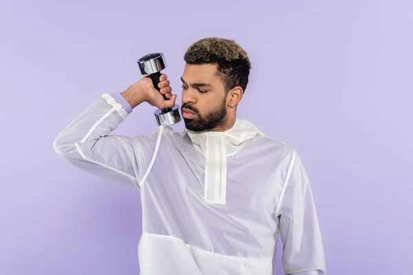 Bearded african american man exercising with dumbbell isolated on purple — Stock Photo