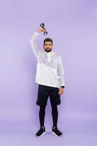 Full length of bearded african american man exercising with dumbbell on purple — Stock Photo