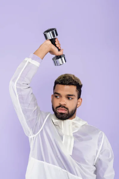 Bearded african american man working out with dumbbell isolated on purple — Stock Photo