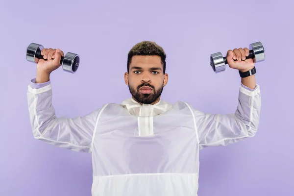 Young african american man exercising with dumbbells isolated on purple — Stock Photo