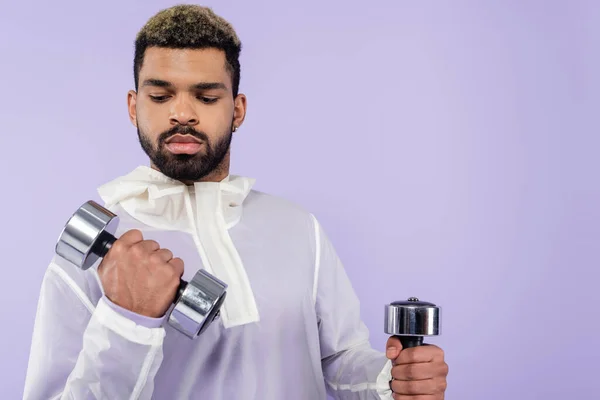 Strong african american sportsman exercising with dumbbells isolated on purple — Stock Photo