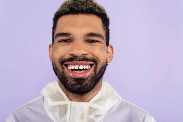 Portrait de heureux homme afro-américain souriant et regardant la caméra isolée sur violet — Photo de stock