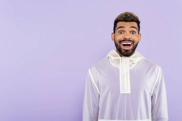 Young and excited african american man with blue eyes isolated on purple — Stock Photo