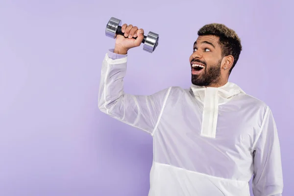 Excited african american sportsman exercising with dumbbell isolated on purple — Stock Photo