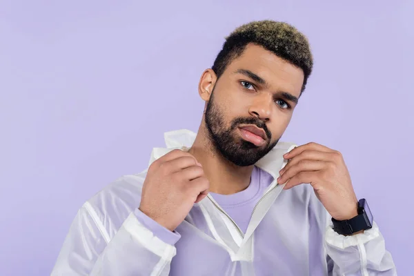 Young african american sportsman with smart watch adjusting collar isolated on purple — Stock Photo