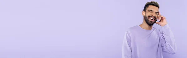 Heureux homme afro-américain en pull parler sur smartphone et rire isolé sur violet, bannière — Photo de stock
