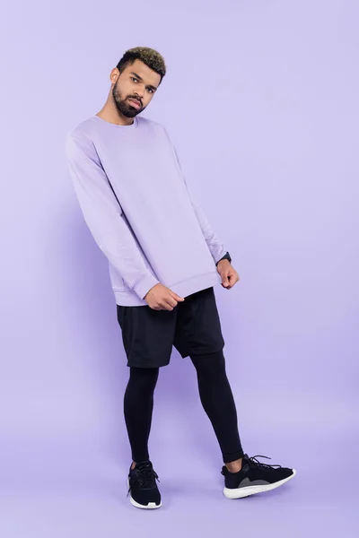 Pleine longueur de barbu homme afro-américain en pull posant sur violet — Photo de stock