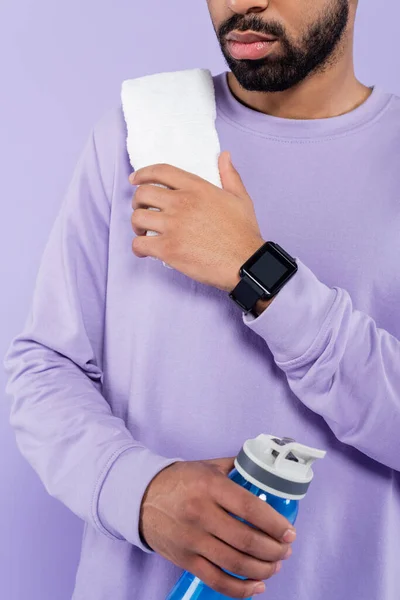 Cropped view of bearded african american man in sweater holding sport bottle with water isolated on purple — Stock Photo