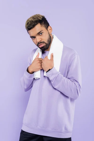 Homme afro-américain barbu en pull tenant une serviette blanche et regardant la caméra isolée sur violet — Photo de stock