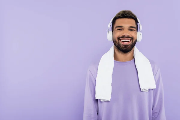 Bärtiger und glücklicher afrikanisch-amerikanischer Mann in drahtlosen Kopfhörern isoliert auf lila — Stockfoto