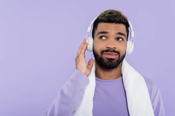 Pleased and bearded african american man in wireless headphones isolated on purple — Stock Photo