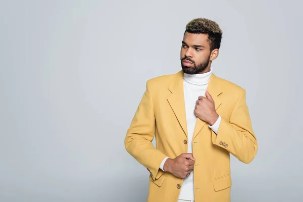 Hombre afroamericano con estilo en chaqueta amarilla mirando hacia otro lado aislado en gris — Stock Photo