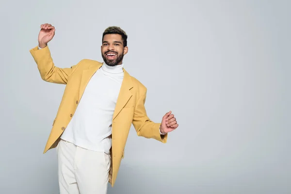 Hombre afroamericano excitado en elegante chaqueta amarilla posando aislado en gris - foto de stock