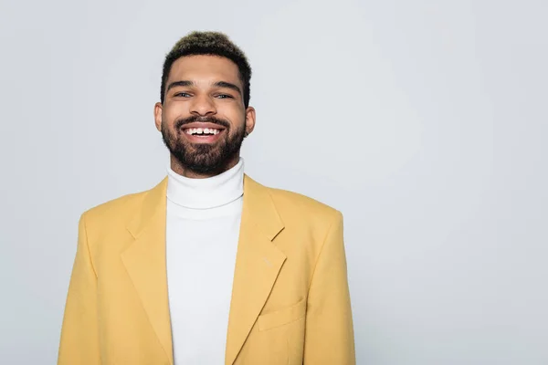 Portrait de heureux homme afro-américain aux yeux bleus en tenue stylée isolé sur gris — Photo de stock