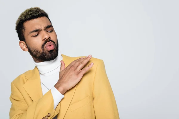 Joven afroamericano hombre en blazer amarillo y polo cuello polvo fuera hombro aislado en gris - foto de stock