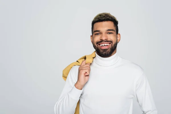 Heureux afro-américain aux yeux bleus à col roulé regardant caméra isolée sur gris — Stock Photo