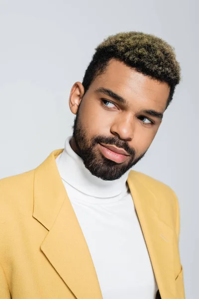 Joven afroamericano hombre con ojos azules mirando hacia otro lado aislado en gris - foto de stock