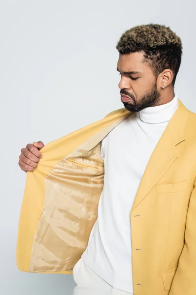 Bearded african american man adjusting yellow stylish blazer isolated on grey — Stock Photo