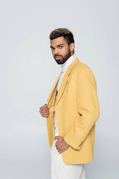 Barbudo hombre afroamericano en cuello alto y blazer con estilo amarillo aislado en gris - foto de stock