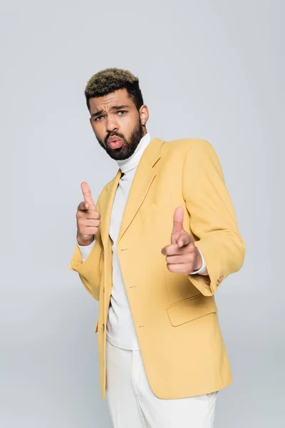 Young african american man in stylish blazer pointing with fingers isolated on grey — Stock Photo