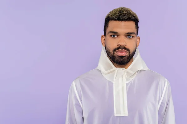 Junger afrikanisch-amerikanischer Mann in trendiger Sportbekleidung blickt isoliert auf lila Kamera — Stockfoto