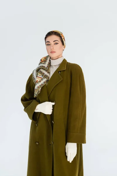 Femme à la mode en mouchoir à motifs et manteau vert regardant la caméra isolée sur blanc — Photo de stock