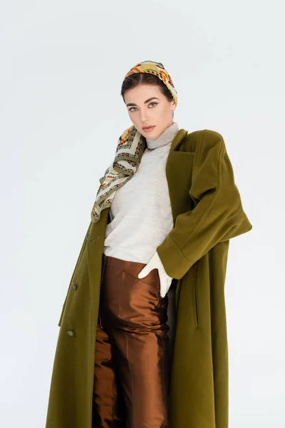 Élégante femme en manteau vert et pantalon marron debout avec la main sur la hanche isolé sur blanc — Photo de stock