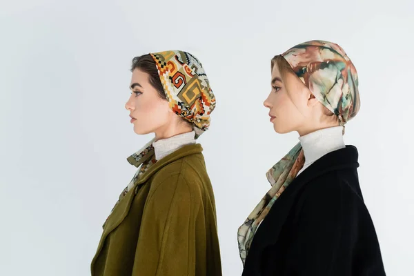 Visão lateral de mulheres em lenços de cabeça estampados isolados em branco — Fotografia de Stock