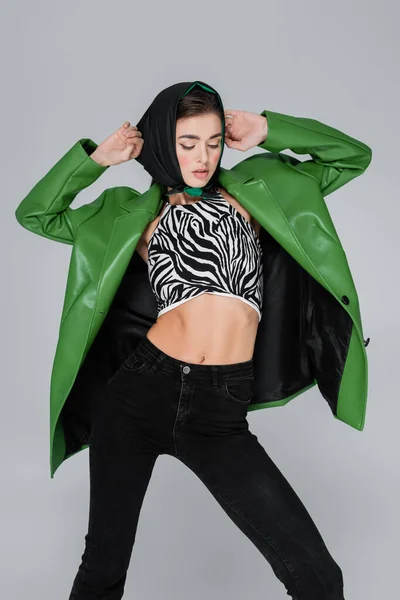 Frau posiert in grüner Jacke und bauchfreiem Oberteil mit Animal Print isoliert auf grau — Stockfoto