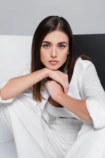 Brunette woman in white clothes looking at camera on grey with black and white — Stock Photo