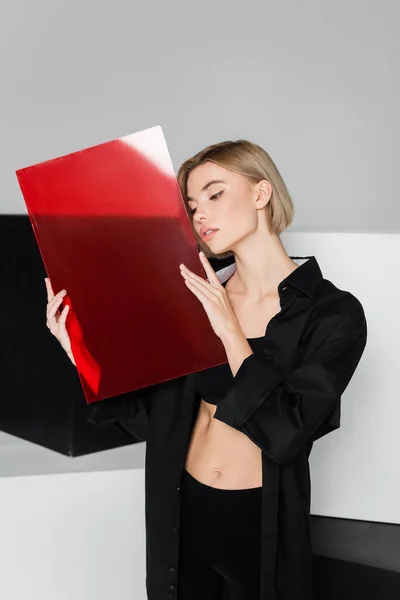 Femme sensuelle posant avec du verre rouge près de cubes noirs et blancs isolés sur gris — Photo de stock