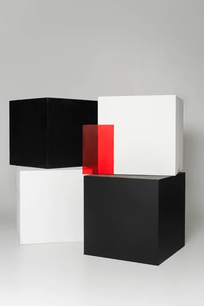 Cubos blancos y negros cerca de vidrio rojo sobre fondo gris - foto de stock