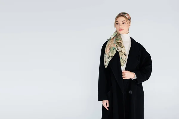 Jeune femme en manteau noir et foulard isolé sur gris avec espace de copie — Photo de stock