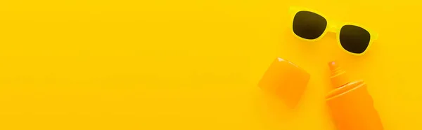 Top view of sunscreen and sunglasses on yellow background, banner — Stock Photo