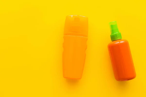 Vista superior de botellas de protectores solares sobre fondo amarillo - foto de stock