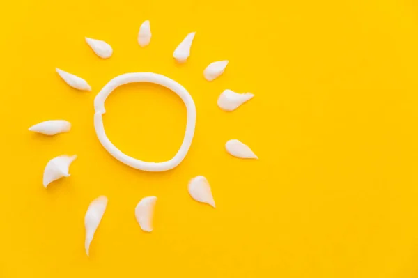 Верхний вид солнца знак от солнцезащитного крема на желтом фоне — стоковое фото