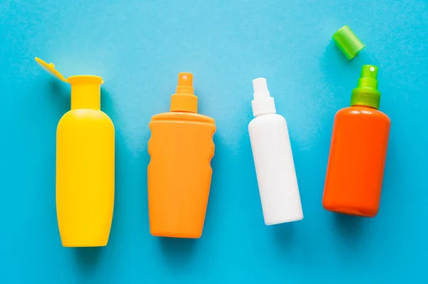 Top view of bottles of sunscreens on blue background — Stock Photo