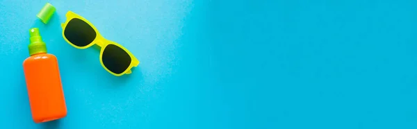 Vista dall'alto della bottiglia di crema solare e occhiali da sole su sfondo blu, banner — Foto stock