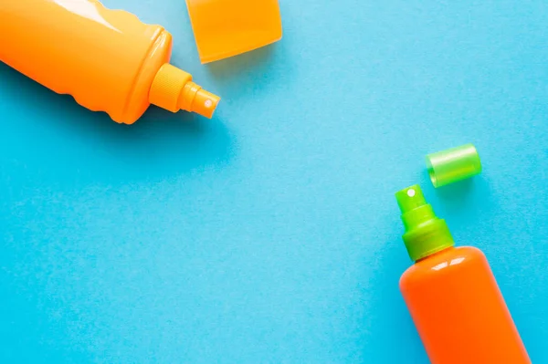 Vue du dessus des bouteilles de crème solaire avec capuchons sur fond bleu — Photo de stock