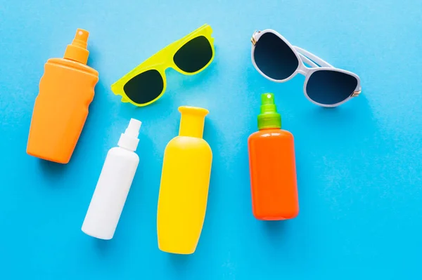 Top view of sunglasses and sunscreens on blue background — Stock Photo