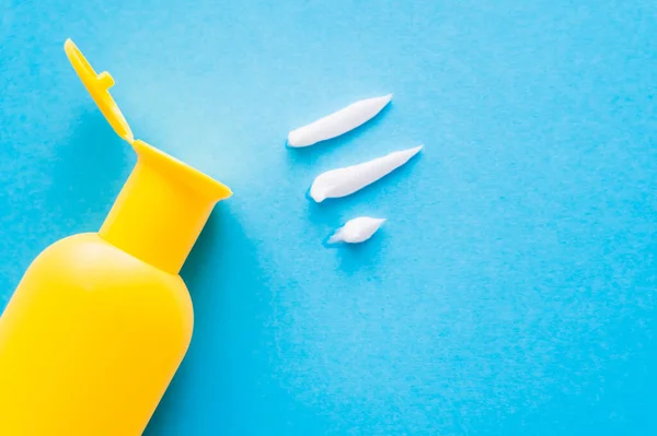 Top view of sunscreen near cream strokes on blue background — Stock Photo