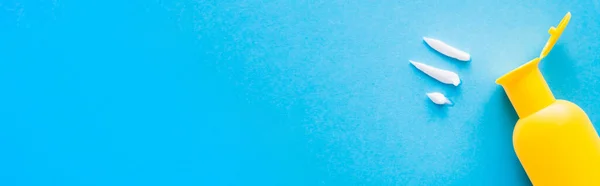 Top view of cream near bottle of sunscreen on blue background, banner — Stock Photo