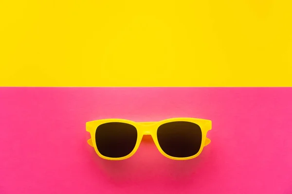 Верхний вид солнцезащитных очков на желтом и розовом фоне — стоковое фото